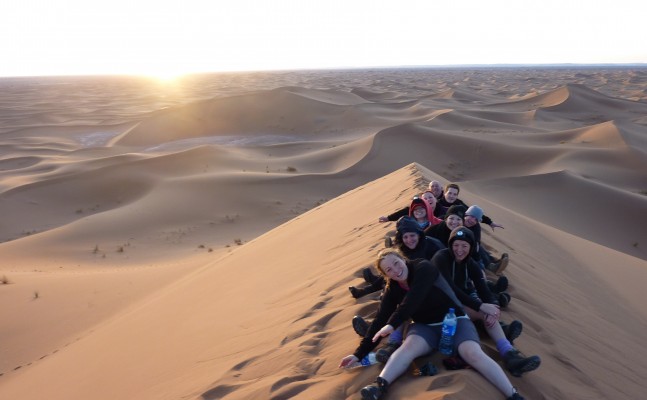 People smiling lying on the desert sand