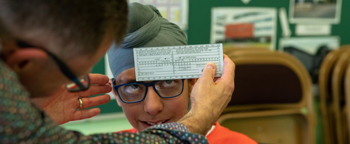 A dispensing optician measuring a boy's glasses