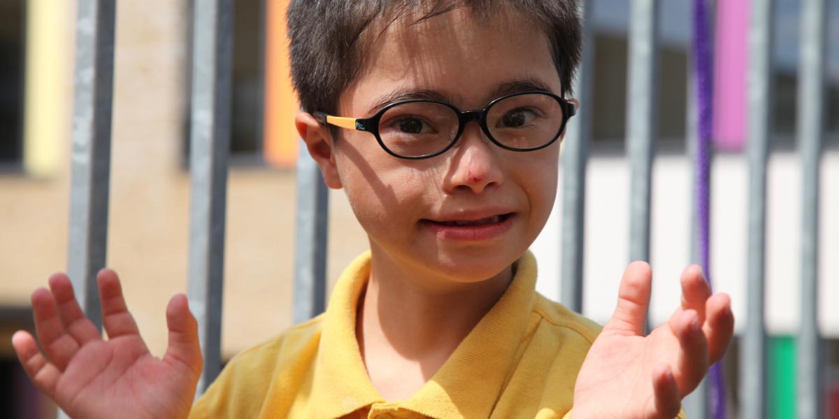 A boy in glasses holds his hands up