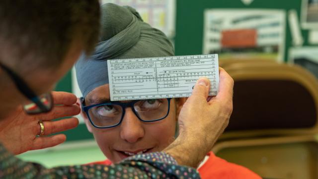 A dispensing optician measuring a boy's glasses