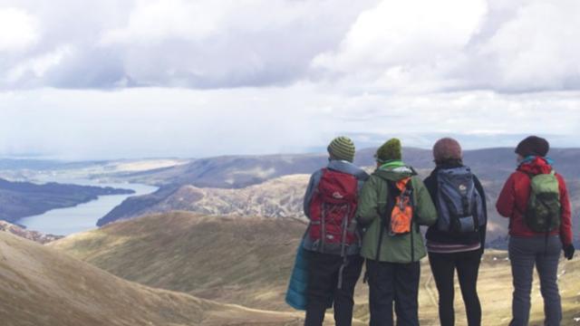 4 people looking out at the mountains on the peaks