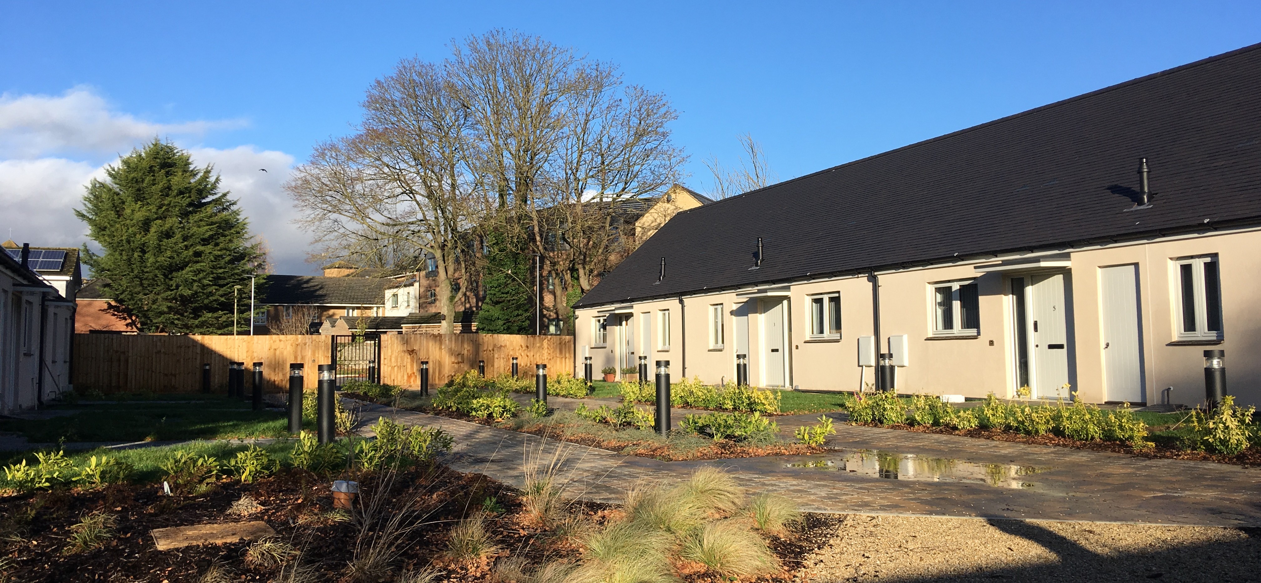 The outside of Bicester Support Service - a group of modern cream-coloured bungalows set within an enclosed courtyard.
