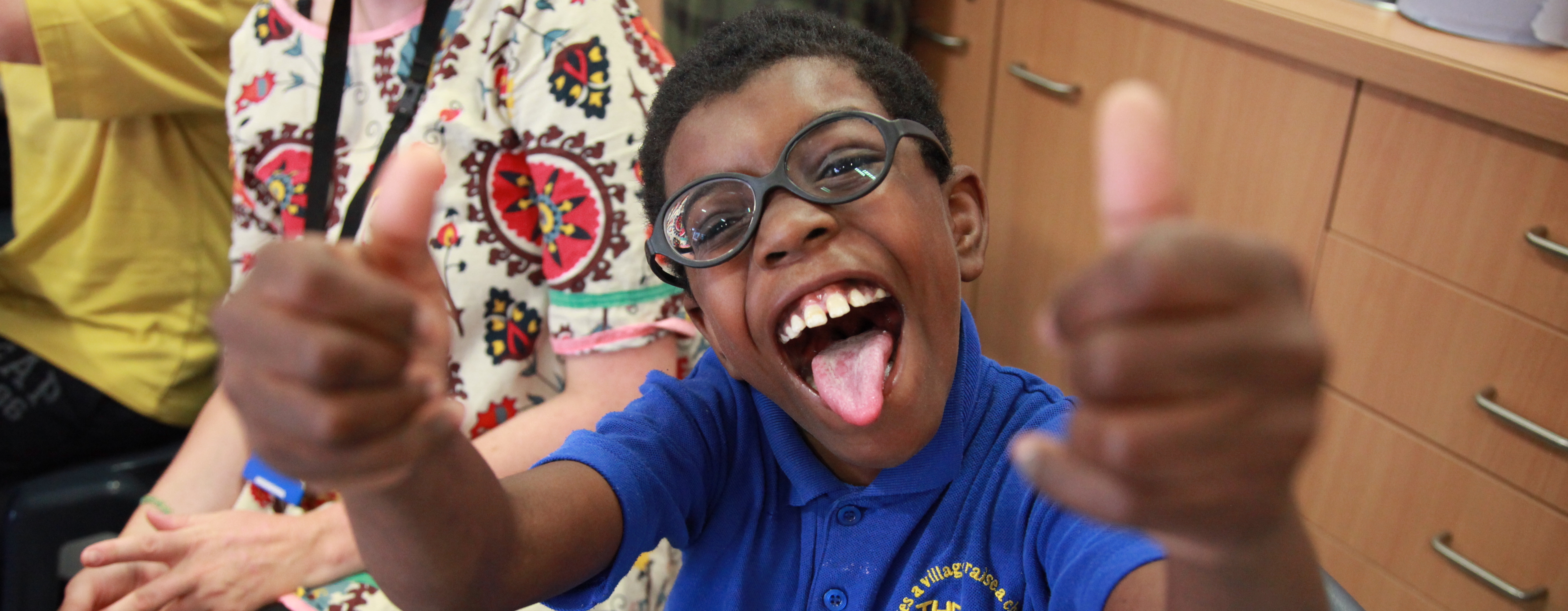A boy in glasses giving a thumbs up