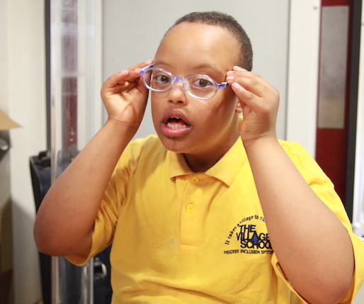 Nasir, a young boy, putting glasses on