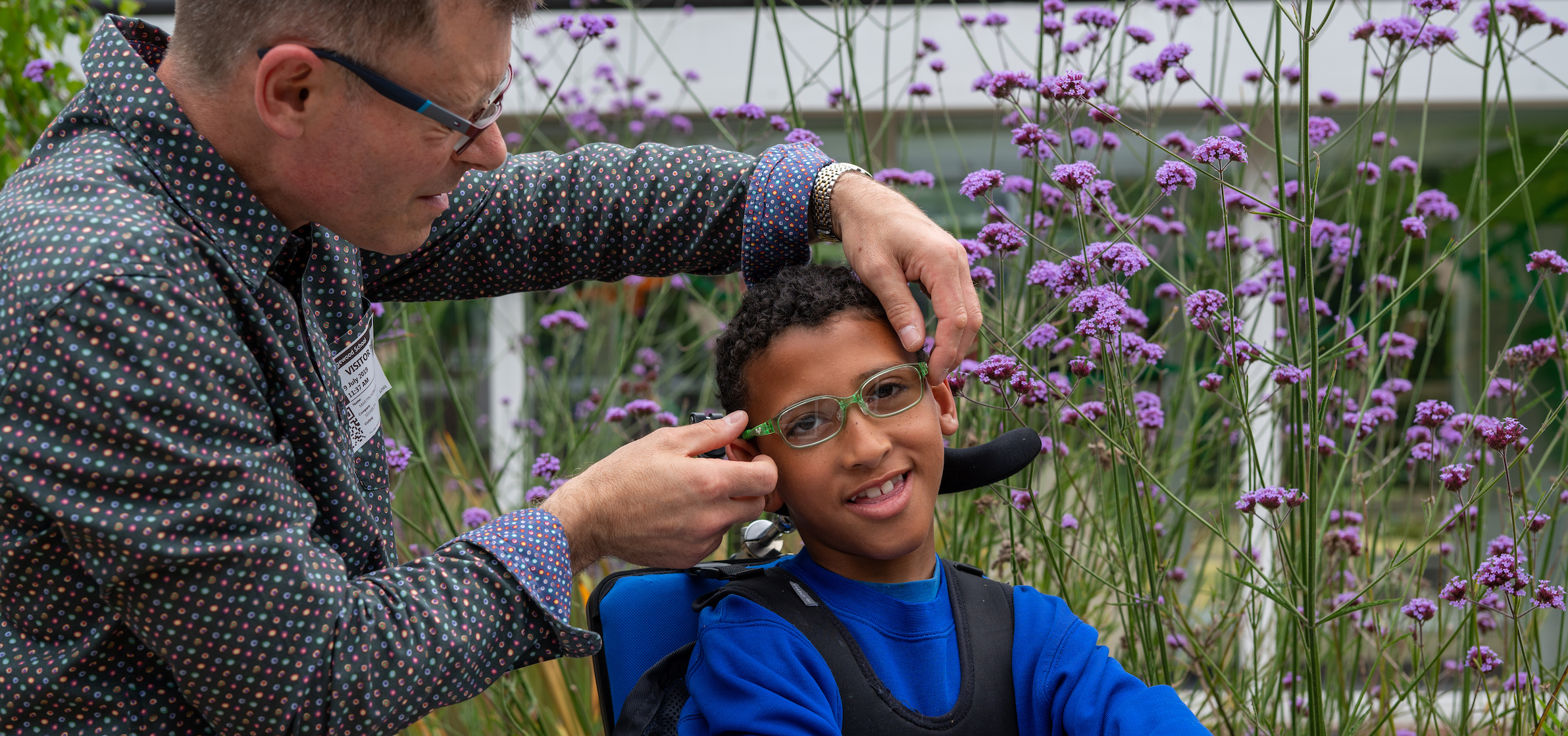 A dispensing optician supports a boy with glasses