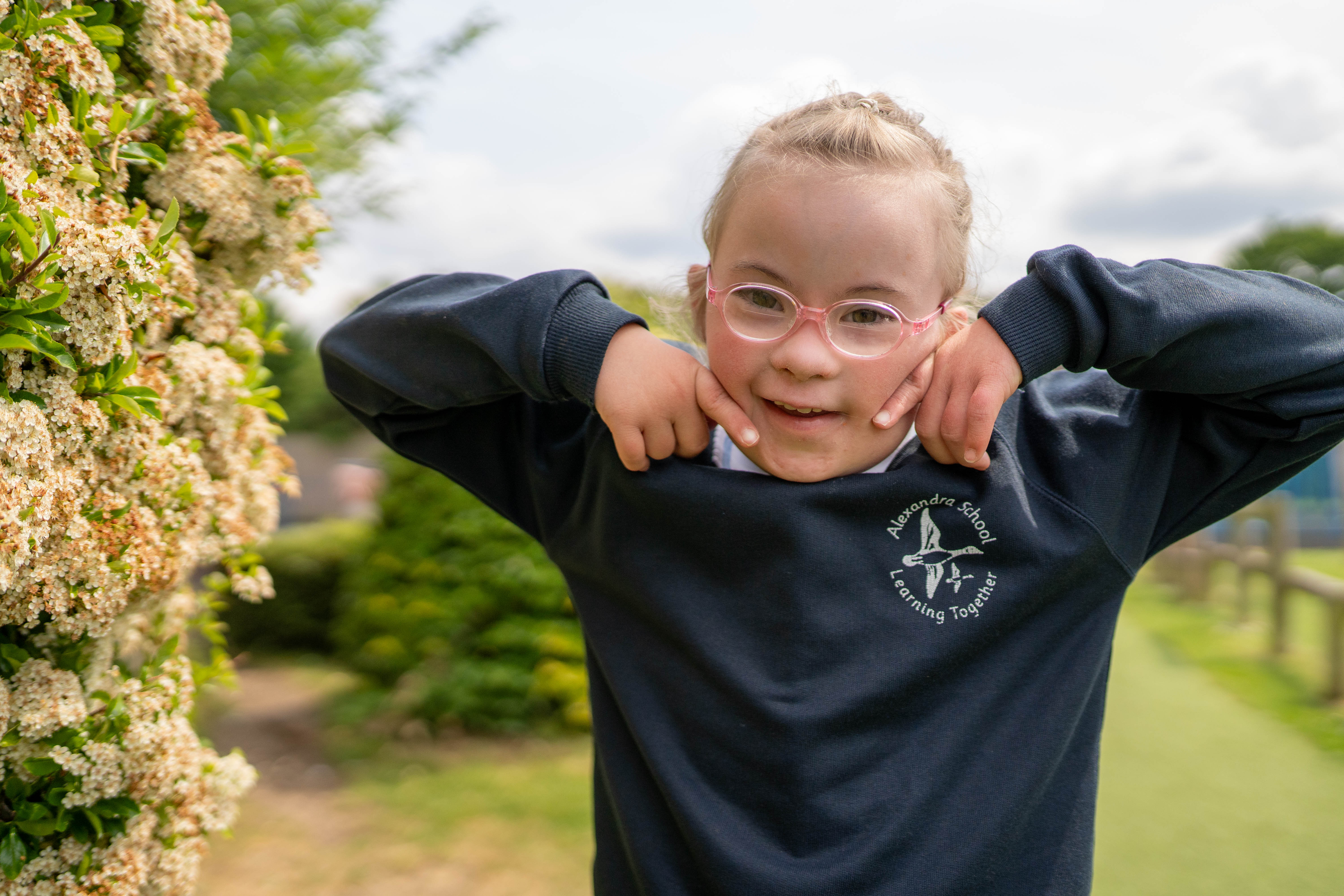 Ellie in her school uniform smiling wearing her glasses 