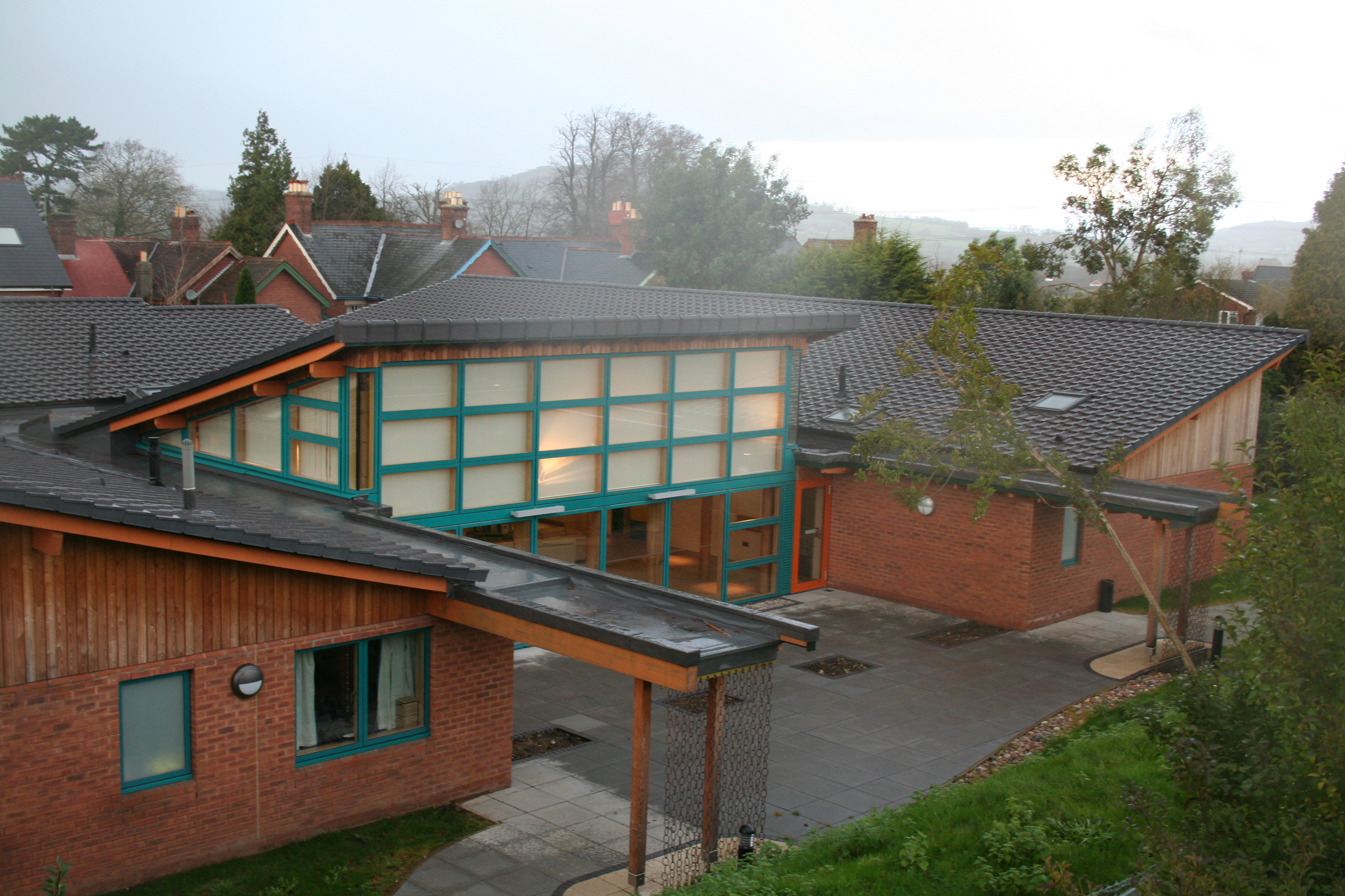 The outside of Devon Support Service in Honiton - a low-rise building with large glazed windows, covered walkways, and a spacious courtyard.