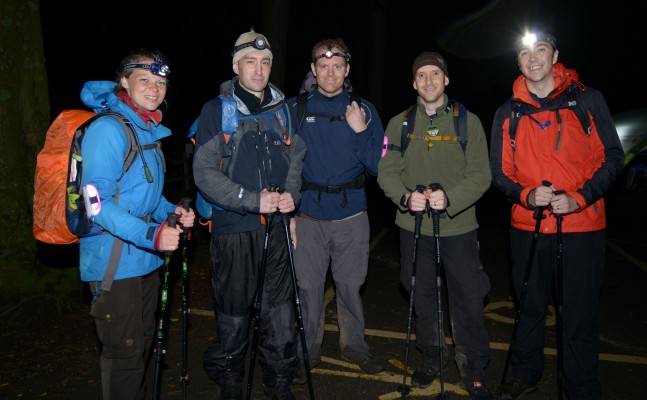 5 men in protective trekking gear and head lamps standing in the dark