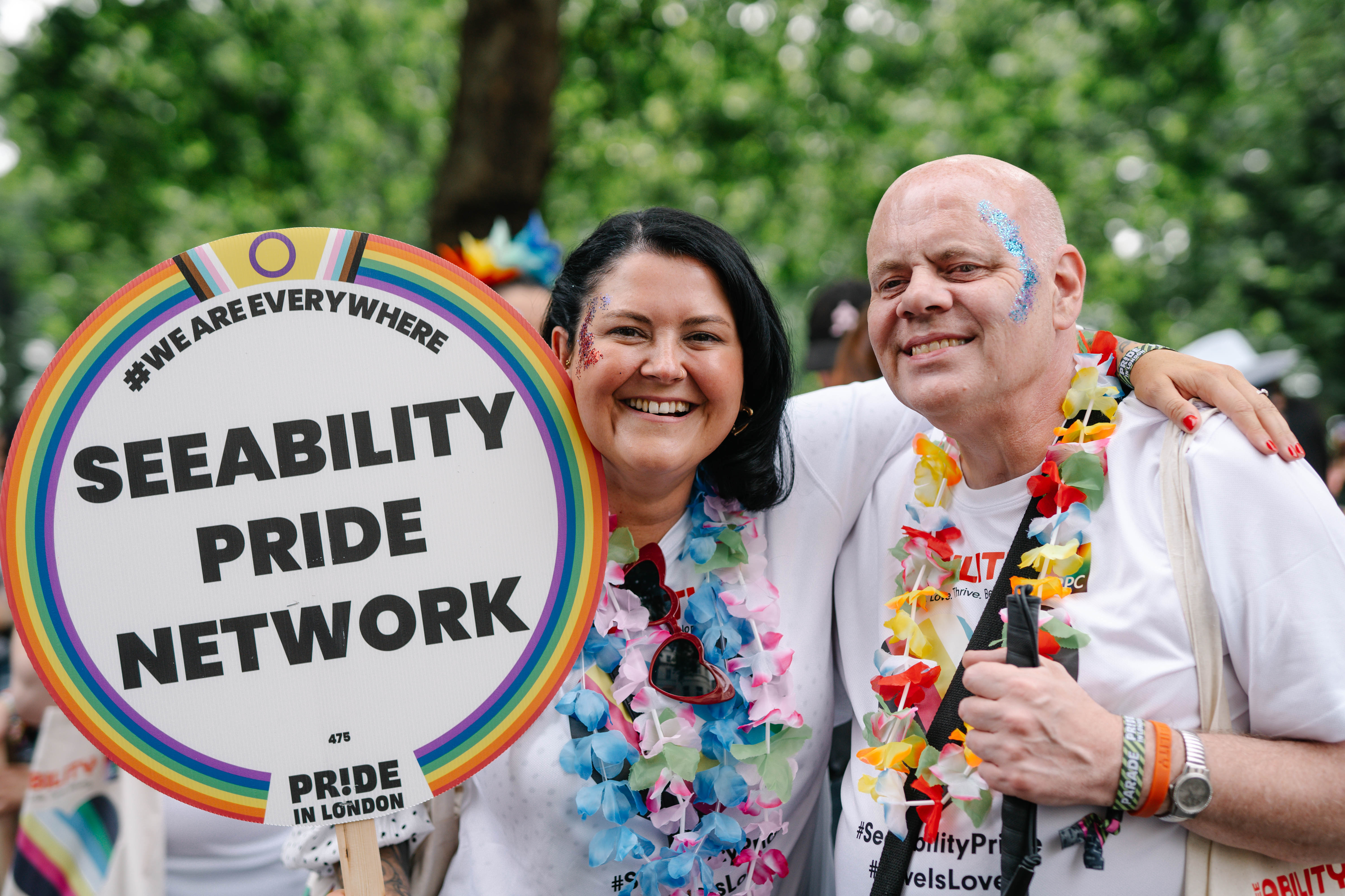 Wayne and Rhi and London Pride with a SeeAbility Pride Network sign