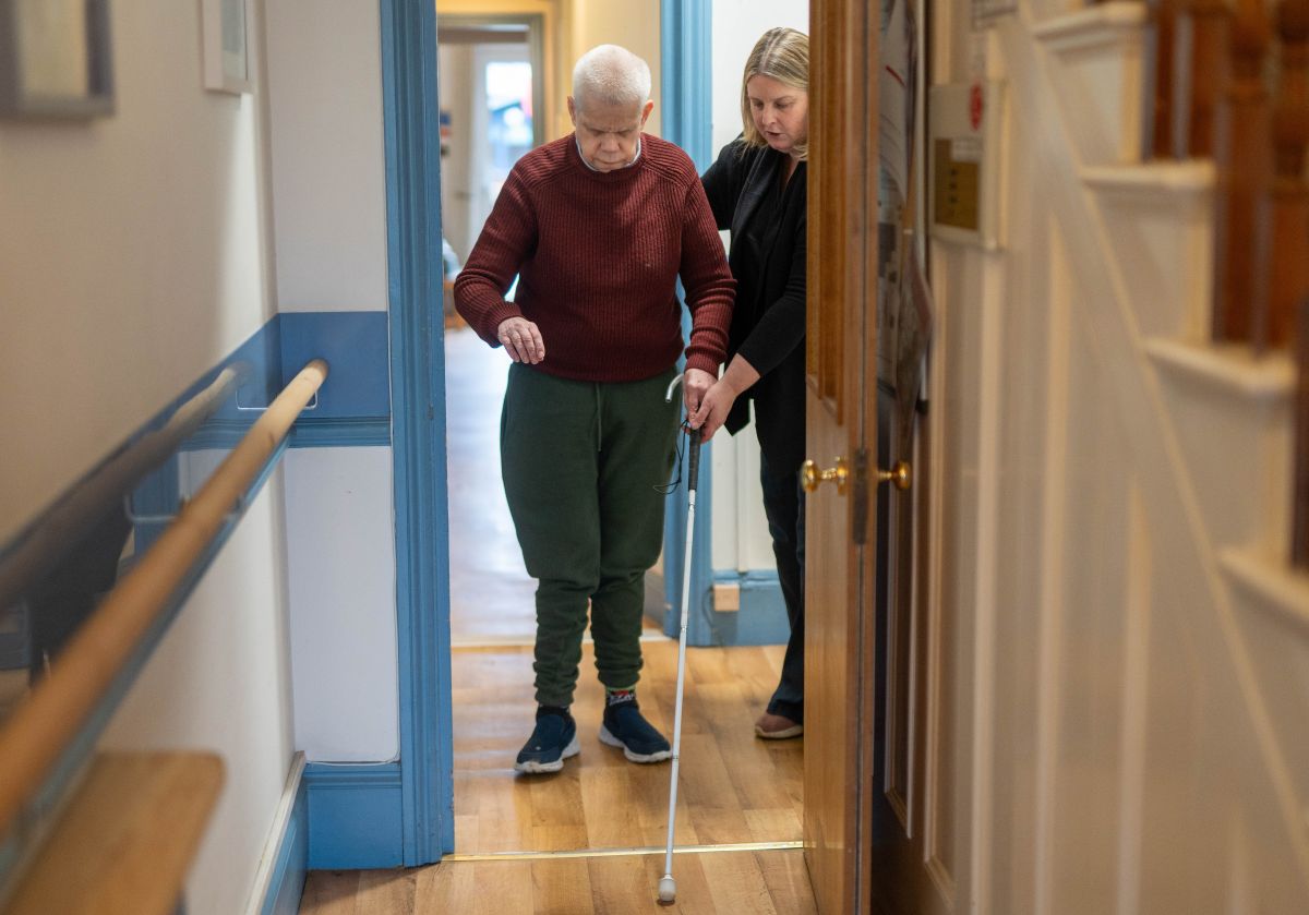Rob being supported to use his cane for sight loss