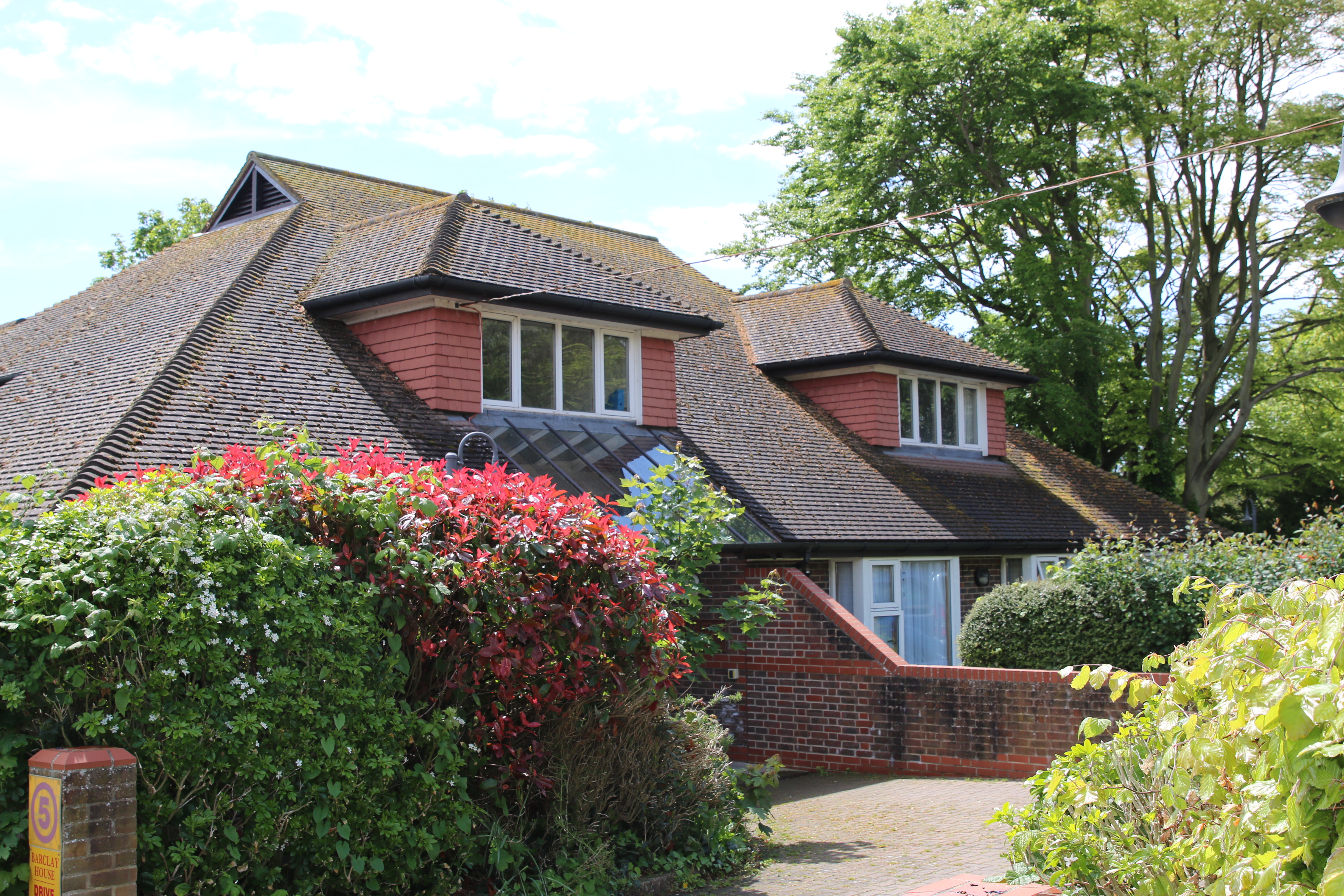 The outside of Barclay House - a bright, modern brick building surrounded by shrubbery of all shapes, colours and sizes