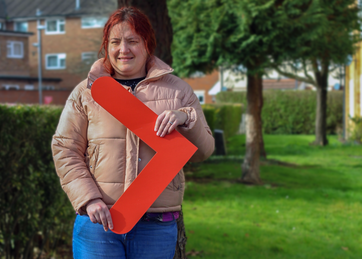 Emma smiles and holds up an orange arrow