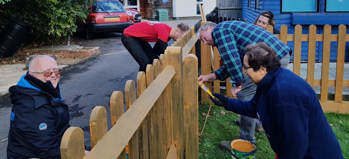 Volunteers painting a fence
