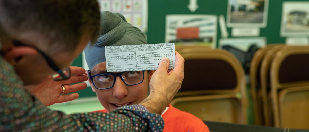 A dispensing optician measuring a boy's glasses