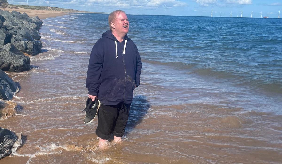 Andrew standing in the sea in Scotland smiling