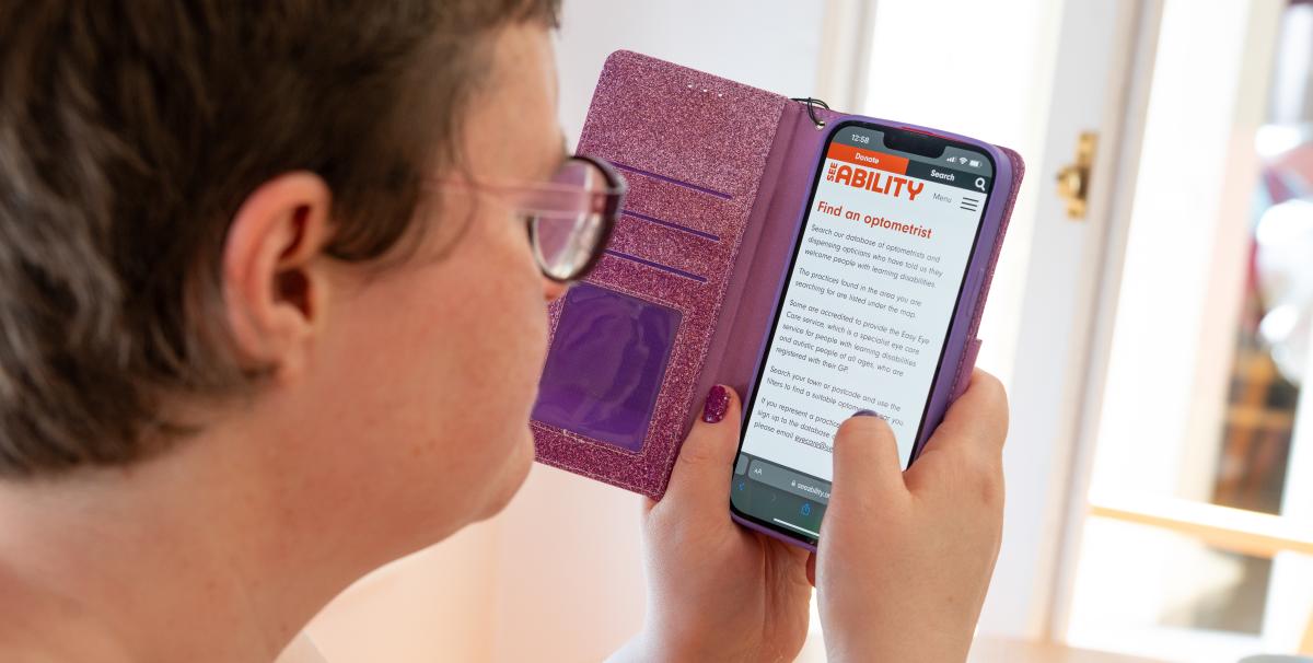 Grace uses her phone to access the SeeAbility website