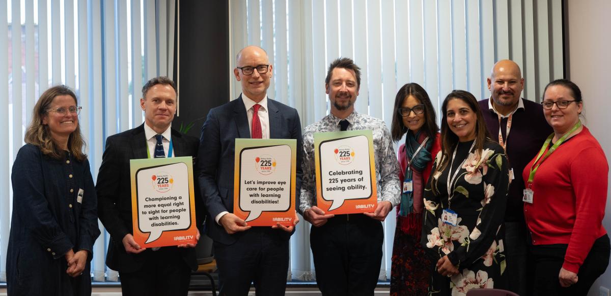 Stephen Kinnock MP with teachers and the eye test team, holding up signs that promote the service