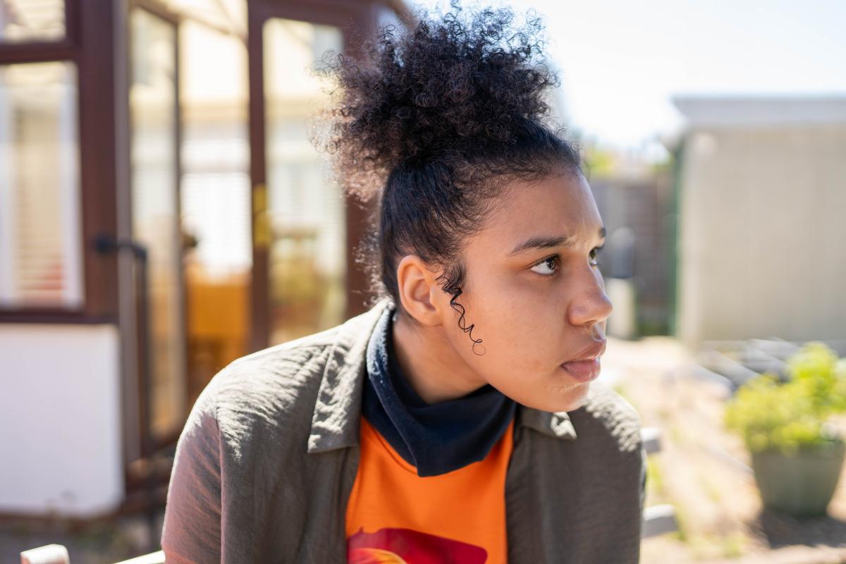 Candace wearing an orange tshirt looking in to the distance