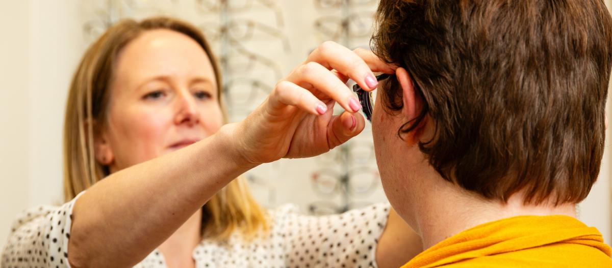A dispensing optician fits Grace's glasses