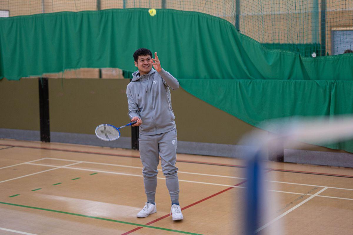 Giban playing badminton in a grey tracksuit