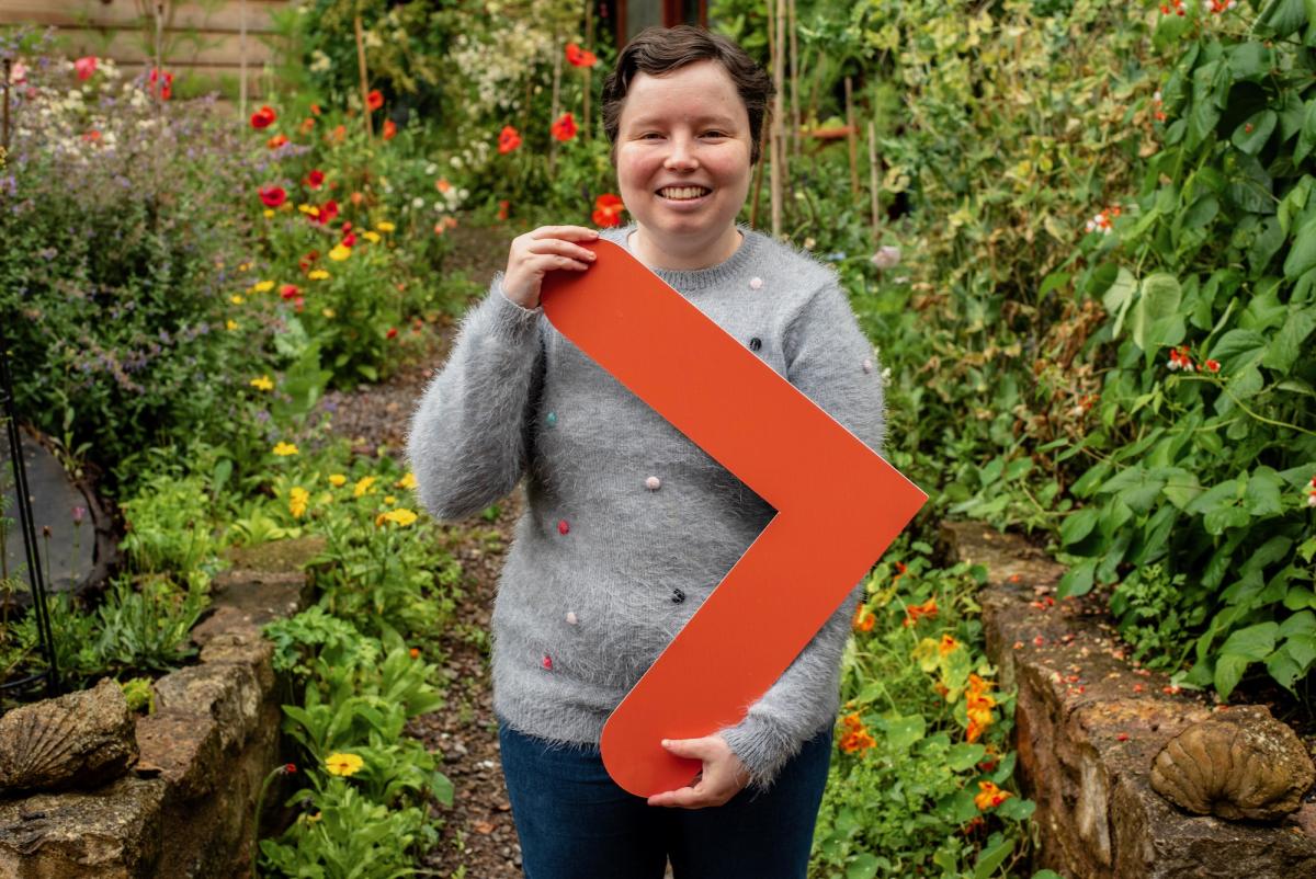 Beatrix holding up an arrow, representing Ready, Willing and Able's logo.