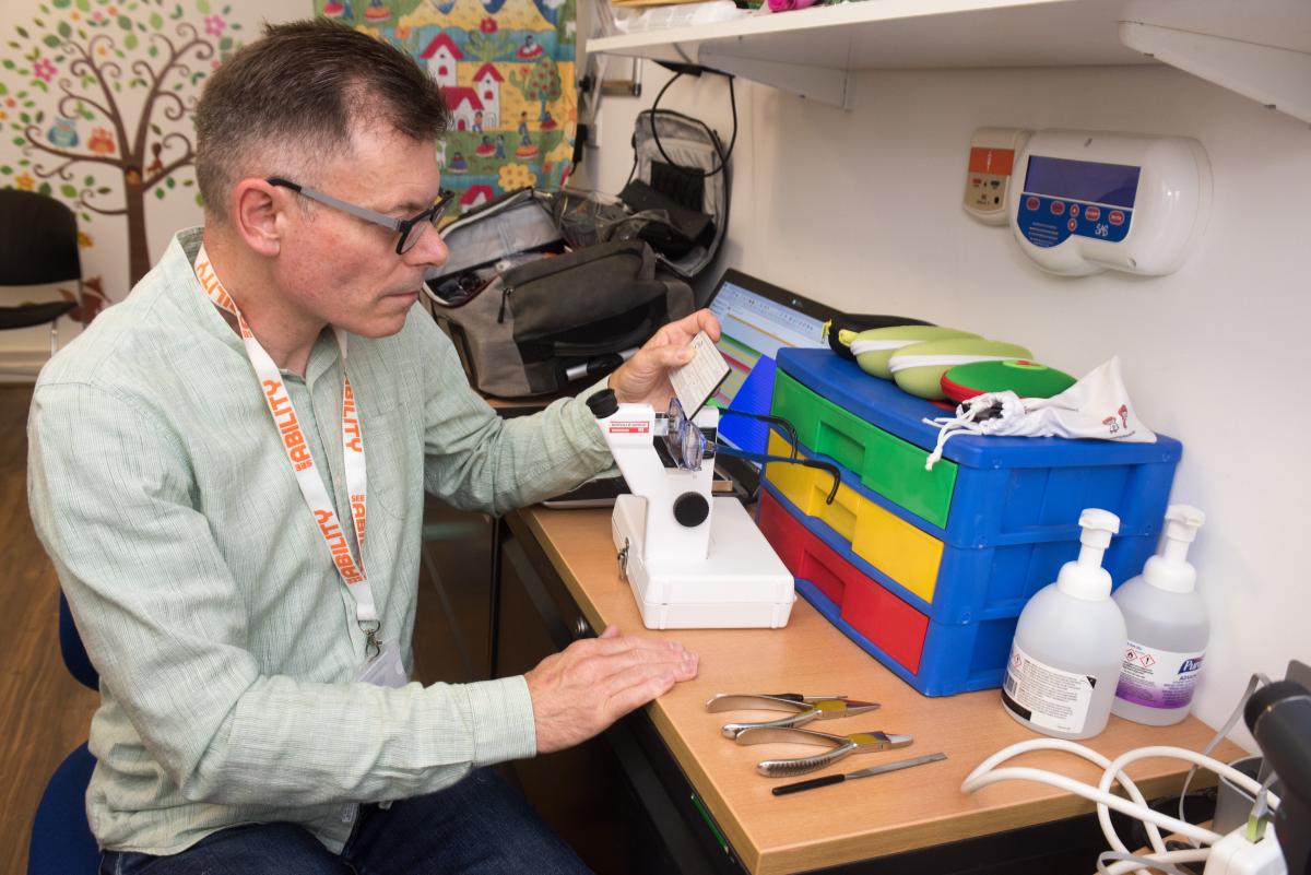 Martyn at a special school measuring the lens of a pair of glasses