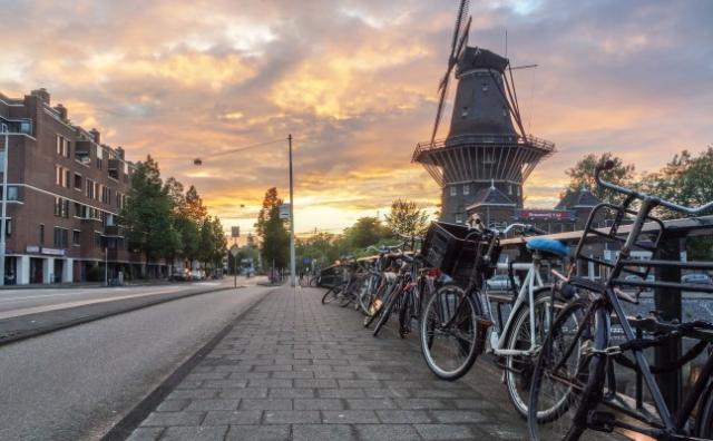 Bikes lined up on the side of the road in Amsterdam at sunset