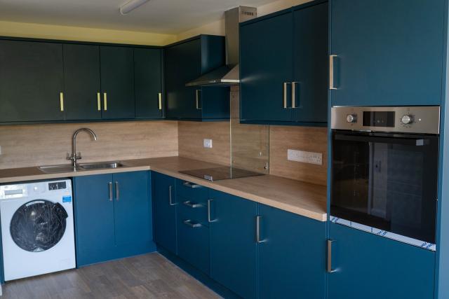 A kitchen at Henbury, showing spacious counter-tops, a built-in oven, washing machine and sink.