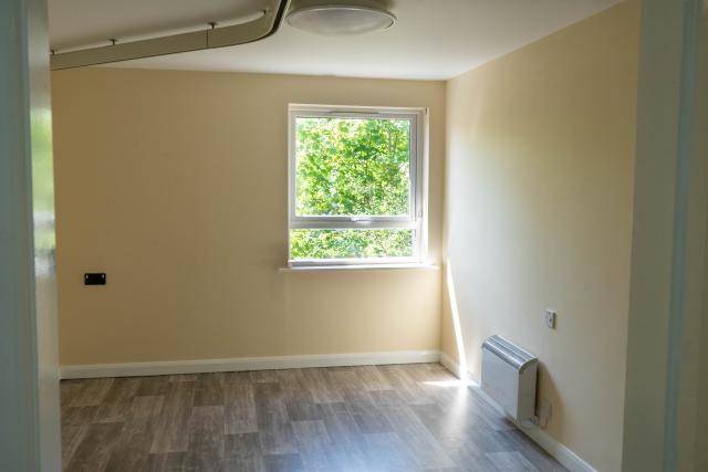 A bedroom in Henbury, showing a bright open space with laminated flooring and a beautiful view out of the window.