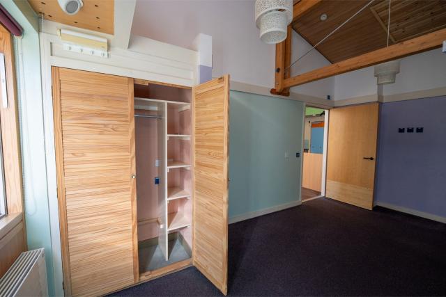 A bedroom at Honiton, showing a large open space complete with a wide open wardrobe.