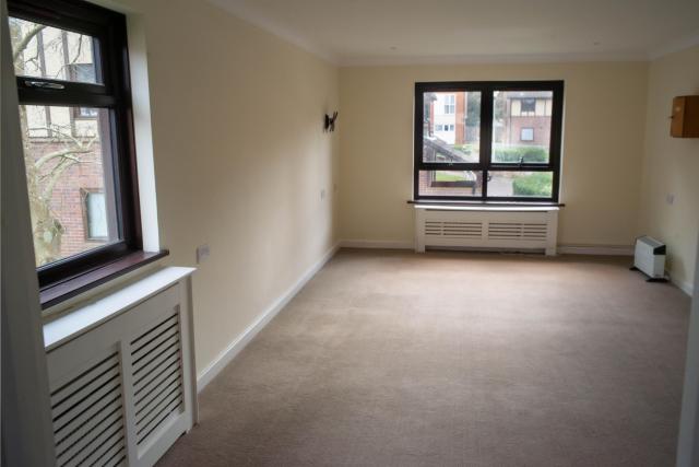 A living room at Spencer Court, showing a wide open space flanked by brightly painted walls and large windows.