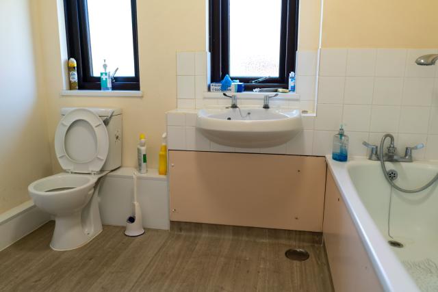 A bright and accessible bathroom at Spencer Court, showing a sink, bath and toilet.