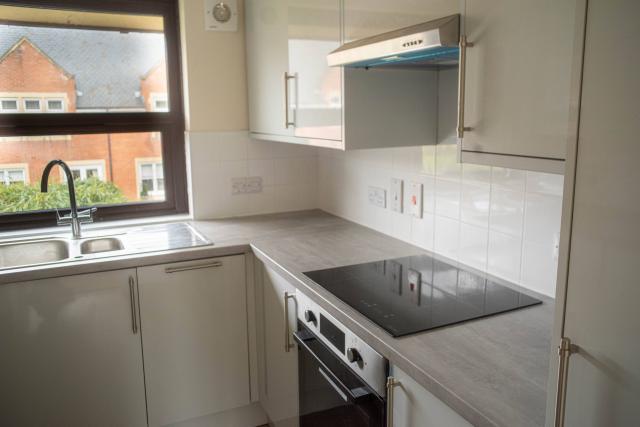A kitchen at Spencer Court, showing bright counter tops, cupboards and an oven.