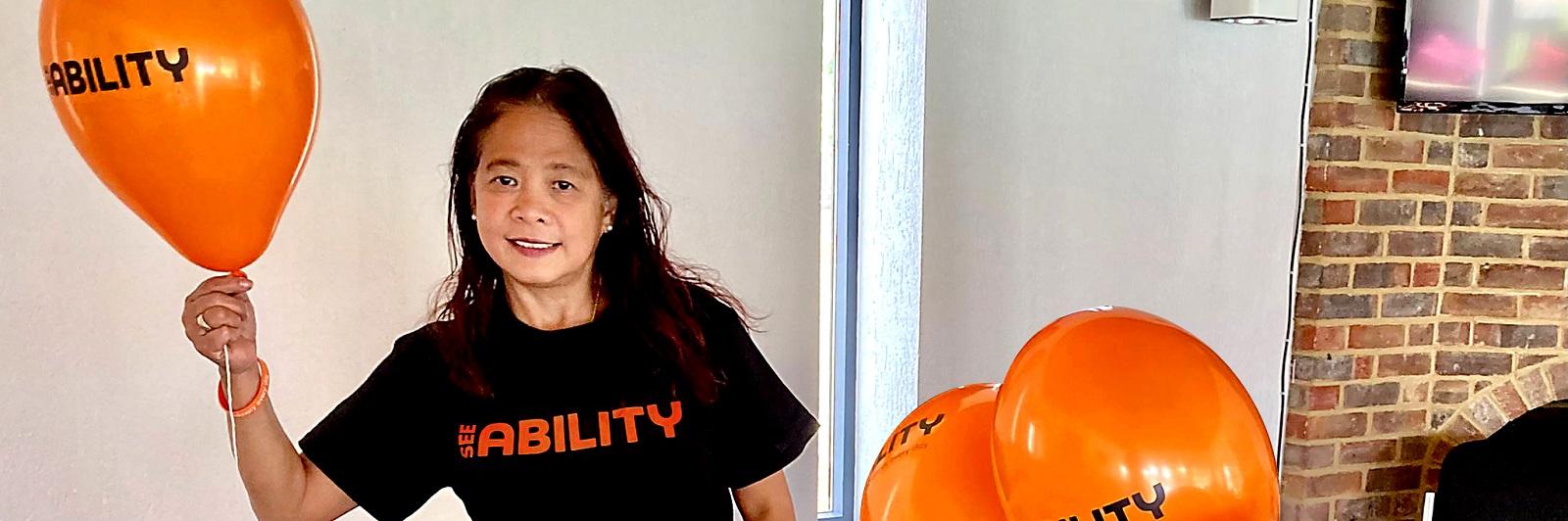 A SeeAbility volunteer holding orange balloons