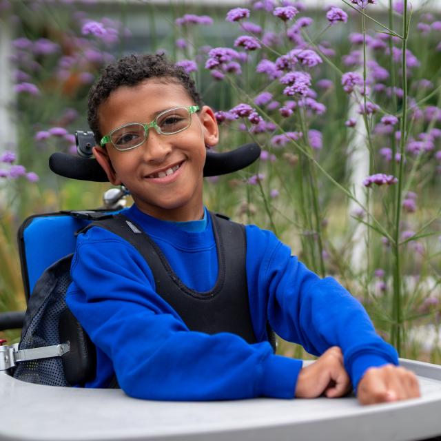 A boy in a wheelchair wearing glasses