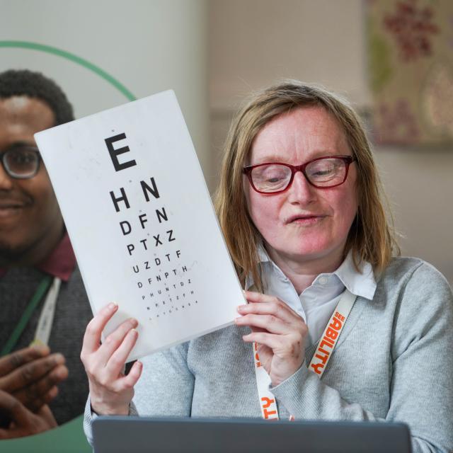 Joanna, an eye care champion, holding up an eye care chart