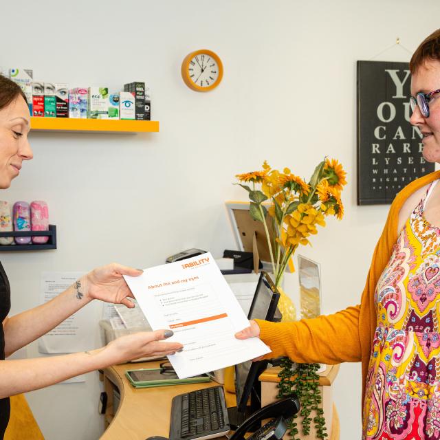 Grace handing an optometrist our 'about me and my eyes' resource 