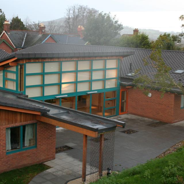 The outside of Devon Support Service in Honiton - a low-rise building with large glazed windows, covered walkways, and a spacious courtyard.
