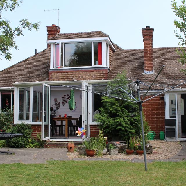 The back garden of a property in Maidstone, showing a spacious red-bricked property surrounded by greenery.