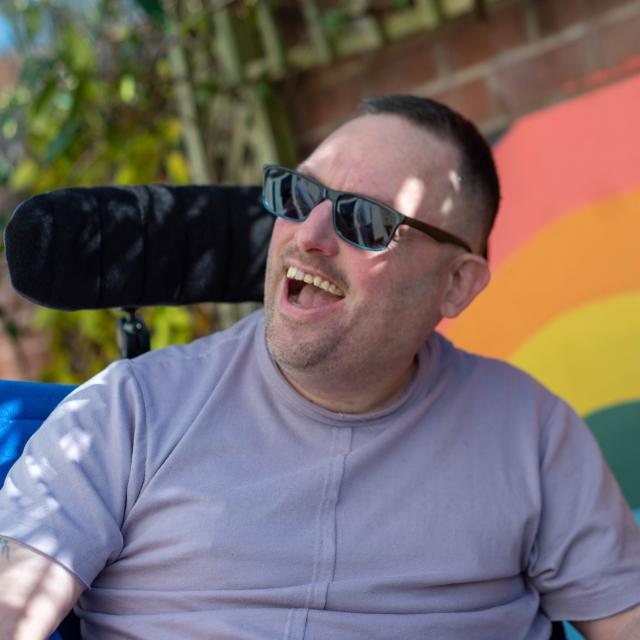 James smiling in front of a rainbow mural