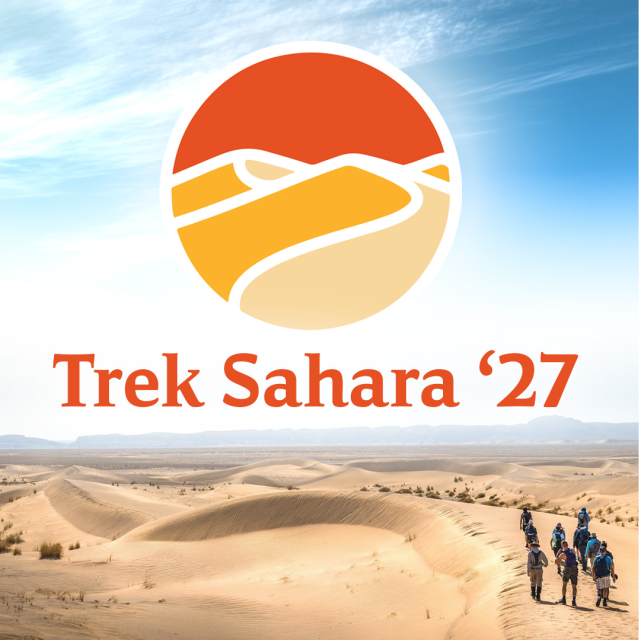 A group of people walking across the vast desert with blue skies with the words Trek Sahara 27
