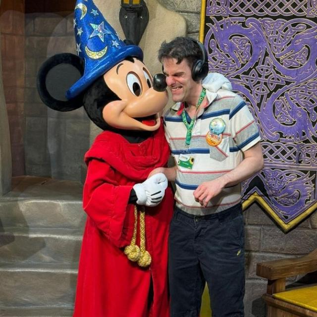 Tom at Disneyworld meeting Mickey Mouse, hugging him and smiling