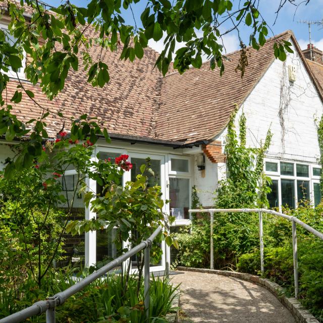 The outside of Applewood, showing a large house and a walkway nestled amongst trees.