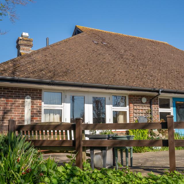 The exterior of Barclay House from the back, showing a seating area surrounded by shrubbery and a fence.