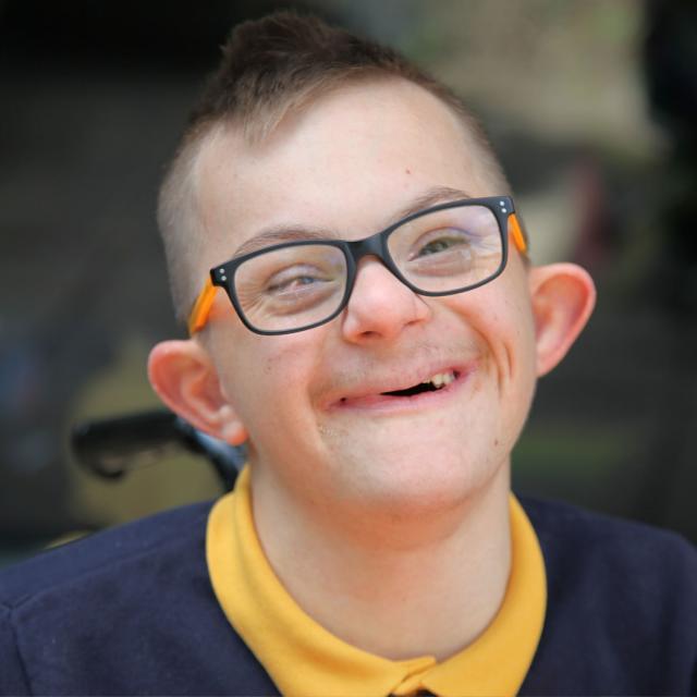 Alexandru smiling at his school with his new glasses