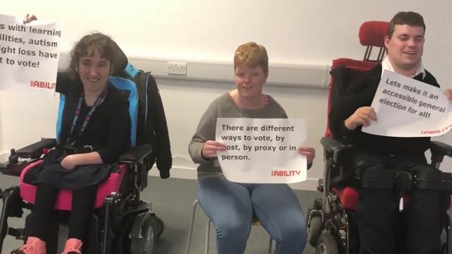 Emily and her colleagues hold up signs asking for disability equality in the last election