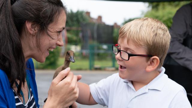 A lady shows a young boy in glasses a duck