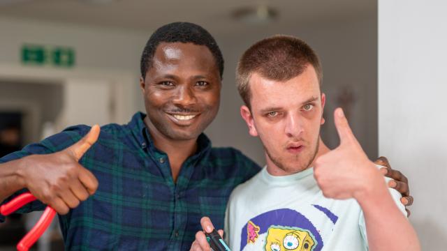 Jake and a support worker smiling with their thumbs up