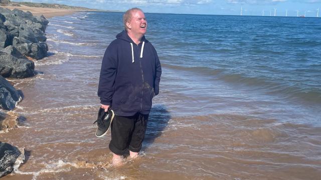 Andrew standing in the sea in Scotland smiling