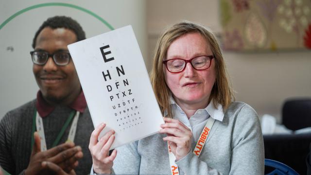 Joanna, an Eye Care Champion, holding up an eye test chart